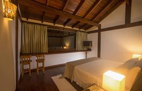 Bangalô com mezanino com uma cama king size e um sofá leito do Bupitanga Hotel